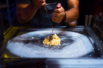Man making ice cream rolls in the food market