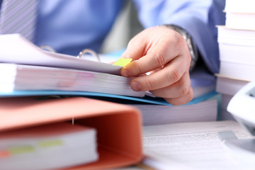 Clerk arm bend over pages in pile of bookmarked documents