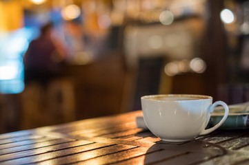 Hot Latte coffee cup on wooden table and glowing bokeh blur background