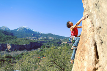 Guy climbing in Greece and beautiful forest and cliff landscape on the background