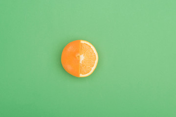 top view of fresh ripe juicy partially cut orange on green background