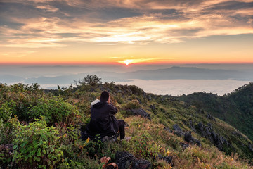 Man hiking with shooting a photo on hill at evening