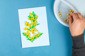 Diy greeting card with mimosa flowers paper balls for March 8 on blue background.