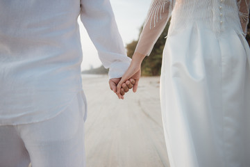 Romantic couple holding hand against the sea at sunset.