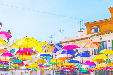 Fototapeta na wymiar Colourful umbrellas urban street decoration. Hanging colorful umbrellas over blue sky,watercolor