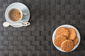 tazzina caffè e piattino biscotti con tovaglietta di materiale sintetico scatto da sopra concetto di colazione