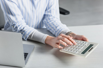 selective focus of woman using calculator near laptop