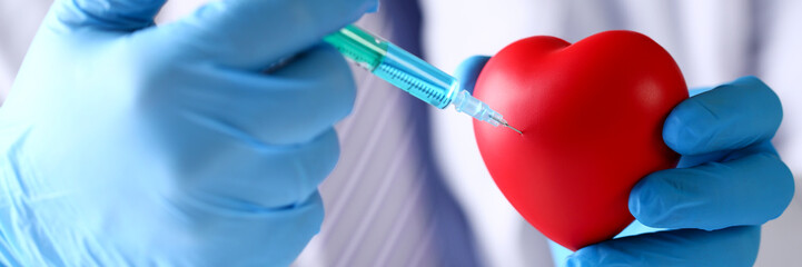 Physician arms wearing protective blue gloves stick needle into heart © megaflopp