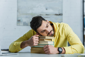 Obraz premium tired man lying on books in modern office
