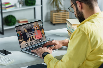Fototapeta na wymiar bearded man looking at laptop with online booking website on screen in modern office