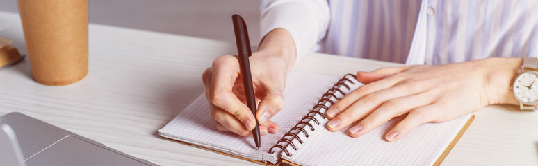 Cropped view of woman writing in notebook