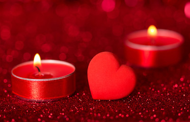 Romantic Valentine's Day. Lit scented candles and red heart on bright sparkling background with bokeh effect