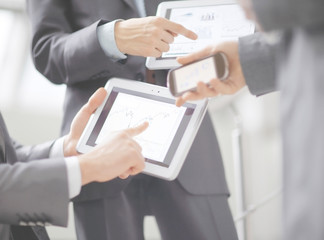 Businessmen at meeting presenting charts on smartphone, tablet