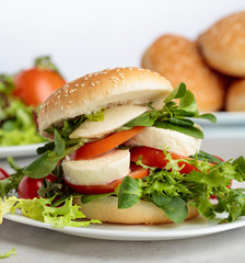 Sandwich with mozzarella, tomato and salad on the kitchen table.