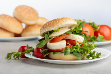 Sandwich with mozzarella, tomato and salad on the kitchen table.