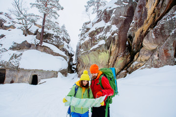 Couple of travelers man and woman with backpacks orient themselves to the terrain, study maps and navigate the route through the mountains. Travel Lifestyle and survival concept.