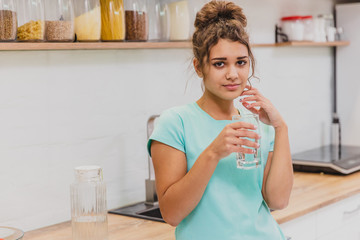 Happy beautiful young woman drinking water. Smiling caucasian female model holding transparent...