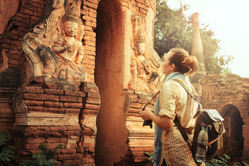 Traveller with backpack resting and looks at Buddhist ancient temple ruins in Indein. Myanmar