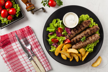 Traditional cevapcici served with baked potatoes. Flat lay. Stone background.