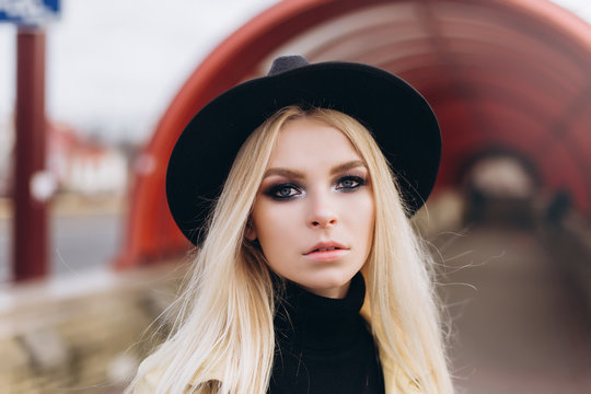 Street fashionable close up portrait of young hipster girl in yellow suit and black hat outdoors