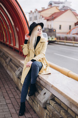 Fototapeta na wymiar Street fashionable close up portrait of young hipster girl in yellow suit and black hat outdoors