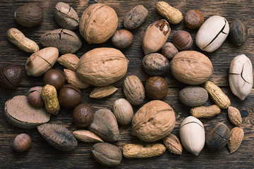 Various sorts of nuts on a brown wooden board background.