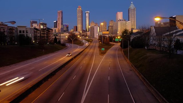 ATLANTA, GEORGIA, USA - January 20, 2019:  Car traffic moving towards the Atlanta Georgia downtown modern skyline at sunrise. Time lapse video