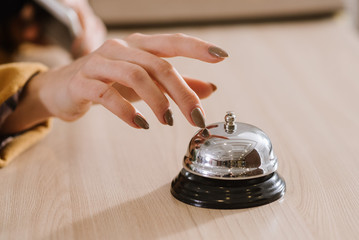 A womans hand on the hotel bell at the reception - obrazy, fototapety, plakaty