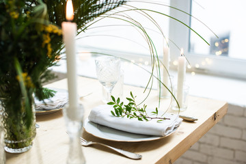 Beautiful springtime table setting with green leaves and mimosa branches, bright white table dinner decoration