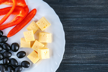 White plate with cheese, paprika, olive on gray surface with copy space. Healthy natural food.