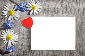 Bouquet of daisies and blue flowers of cucumber grass with heart on a wooden background vintage, background for Valentine's day, flat lay, copy space, mock up