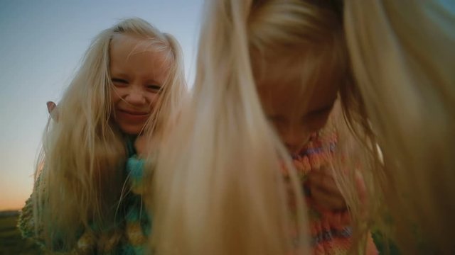 Slow Motion Low Angle Shot Funny Twin Sisters Shake Long Hair Over Camera On Nice Spring Evening