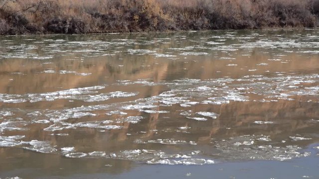Ice floating down the Colorado River melting in winter reflecting cliffs in Moab Utah.