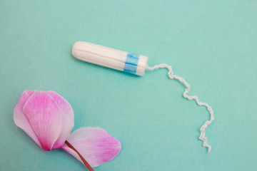 Menstrual tampon on a blue background. Menstruation cycle. Hygiene and protection.