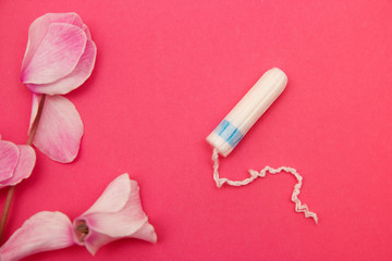 Hygienic tampons on a pink background with flowers.