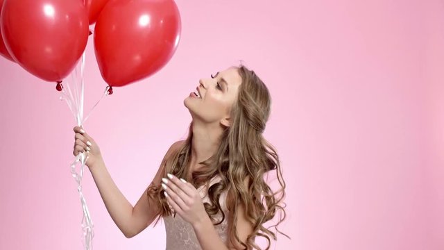 Happy woman with red balloons blowing a kiss