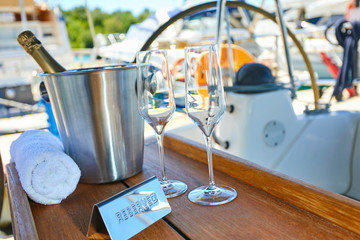 Fototapeta na wymiar Romantic luxury evening on cruise yacht with champagne setting. Empty glasses and bottle with champagne and tropical sunset with sea background