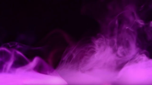 purple smoke waves over calm water surface at dark background