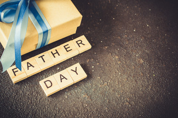 Happy Father's day greeting card with decorated gift box on dark background.