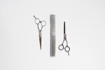 flat lay pair of hairdressing scissors and a comb isolated on white background
