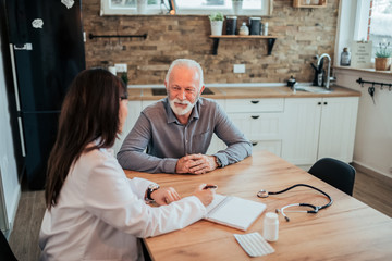 Female doctor talking to a senior patient during home visit.