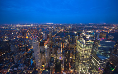 New York City Manhattan aerial panorama view at night with office building skyscrapers skyline illuminated by Hudson River.