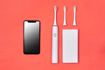 Smart electric toothbrush. Controlled by the application on the smartphone. With power bank. Modern technology for health. Healthy teeth. Dentistry. Medical robot. Pink coral background