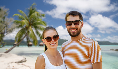 Obraz premium travel, tourism and people concept - happy couple in sunglasses outdoors in summer over tropical beach background in french polynesia