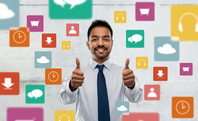 business, office worker and people concept - smiling indian businessman in shirt with tie showing thumbs up over app icons on grey background