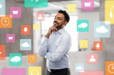 business, technology and multimedia concept - smiling indian businessman with app icons over office background