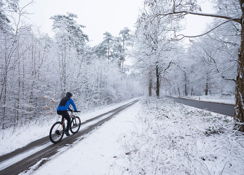 man on mountain bike follows trail in snow during winter in the netherlands near utrecht and austerlitz