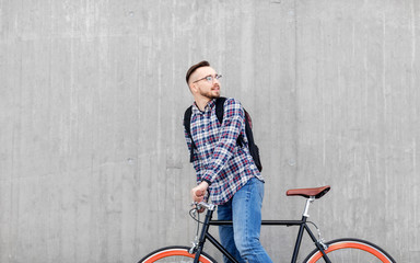 Fototapeta na wymiar travel, tourism and lifestyle - happy young hipster man in earphones with fixed gear bike and backpack on city street