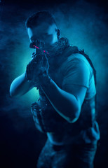 Fototapeta na wymiar the man in military special clothes posing with a gun in his hands on a dark background in the haze