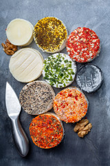 Assortment of French fresh white soft goat cheeses with different tastes topping made with herbs, paprika, indian curry, bruscetta, chives and dried tomatoes